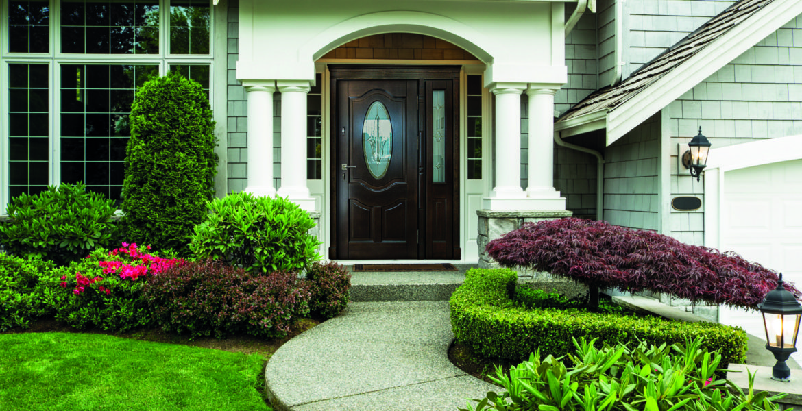 Front Door to Home Front Door to home surrounded by seasonal plants and part yard and sidewalk in forefront