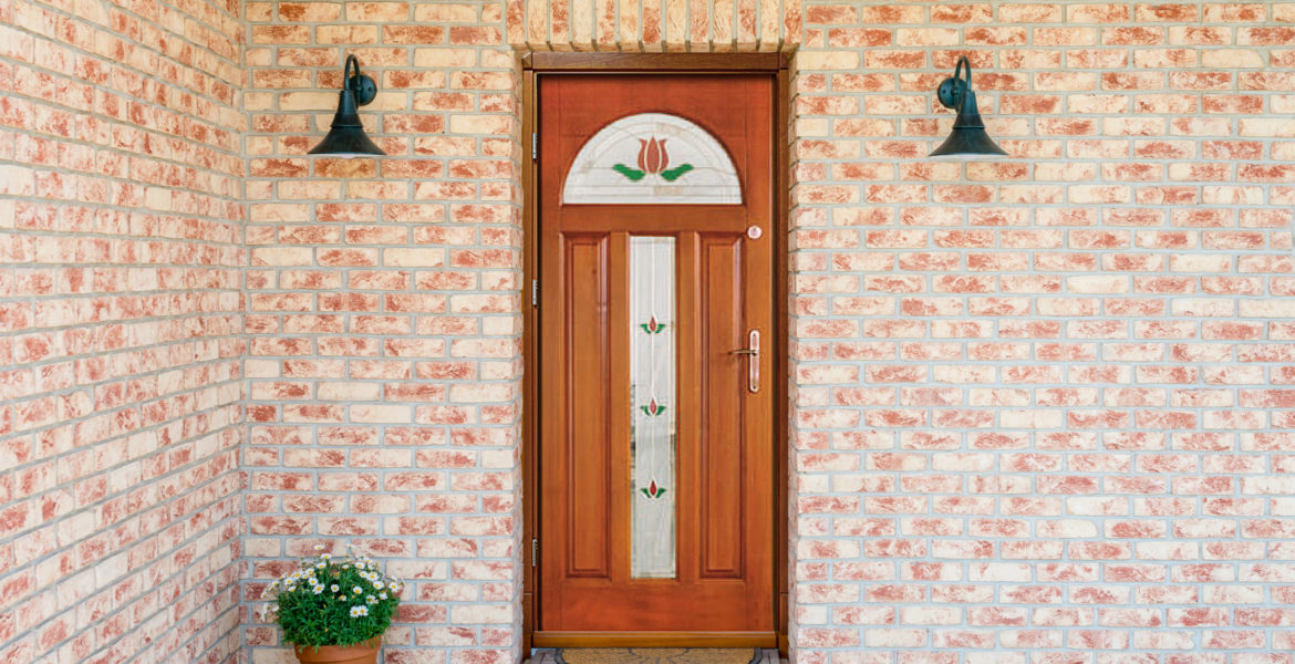entrance of a home - stylish wooden front door in a detached house - embedded in a brick wall